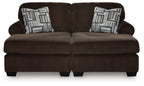 Chocolate loveseat-style sectional with two seat cushions and patterned throw pillows