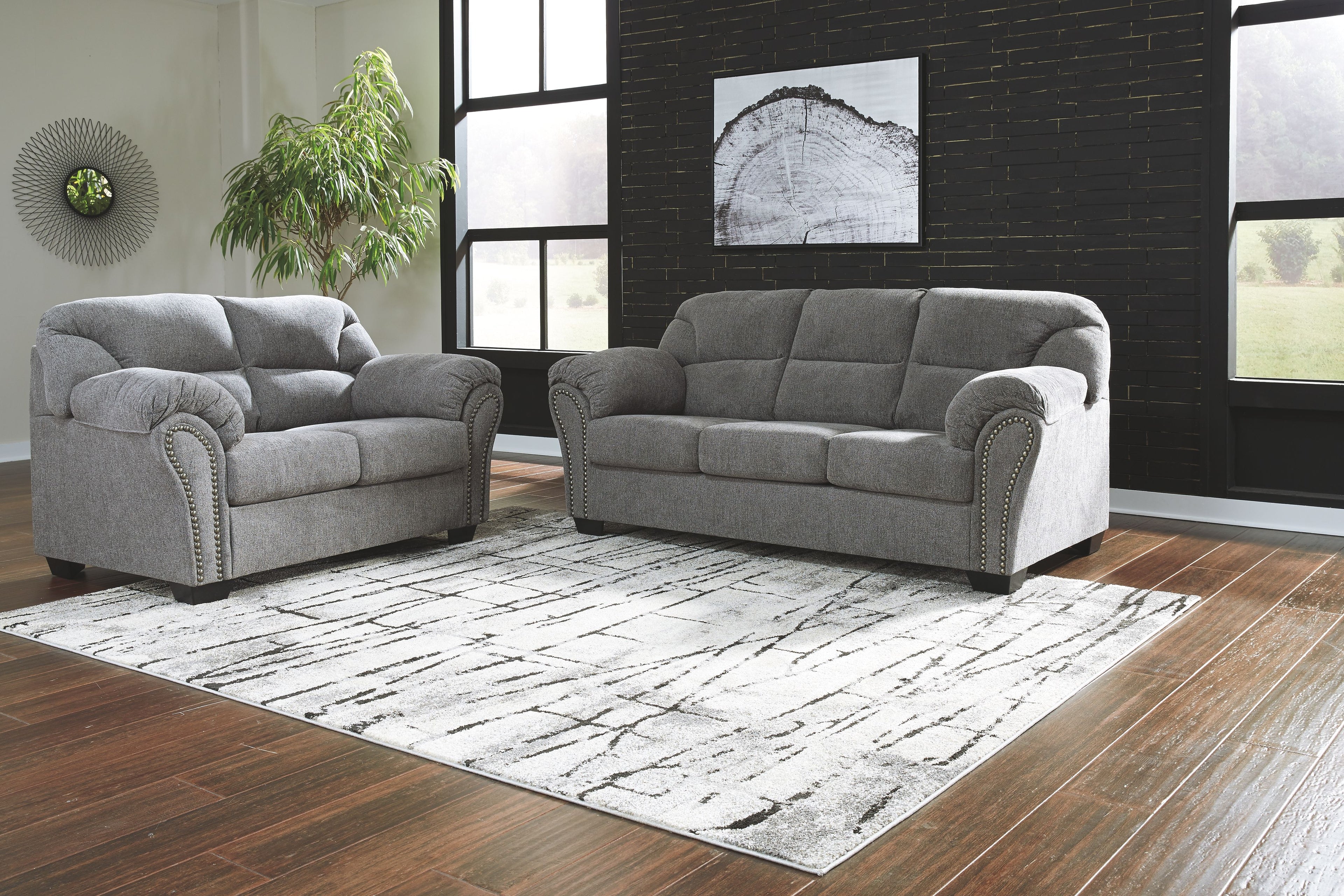 Dark gray sofa and loveseat set with button-tufted backs, rolled arms, and stud trim