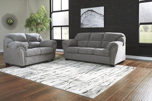 Dark gray sofa and loveseat set with button-tufted backs, rolled arms, and stud trim