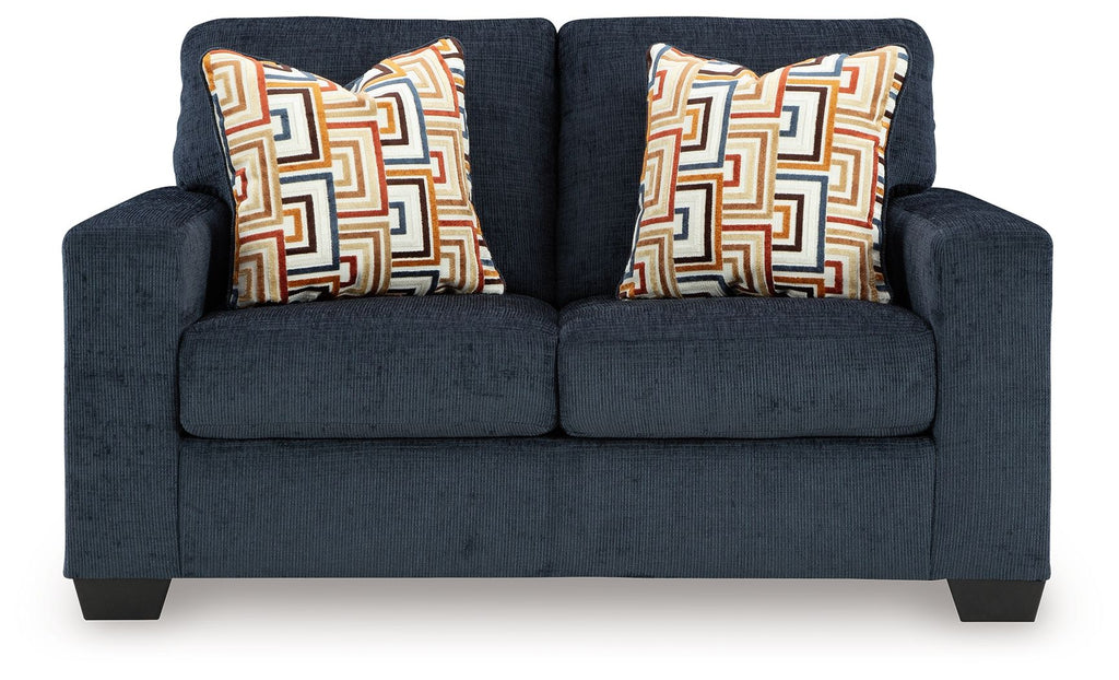 Dark navy loveseat with two patterned throw pillows and thick, square armrests.