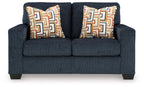 Dark navy loveseat with two patterned throw pillows and thick, square armrests.