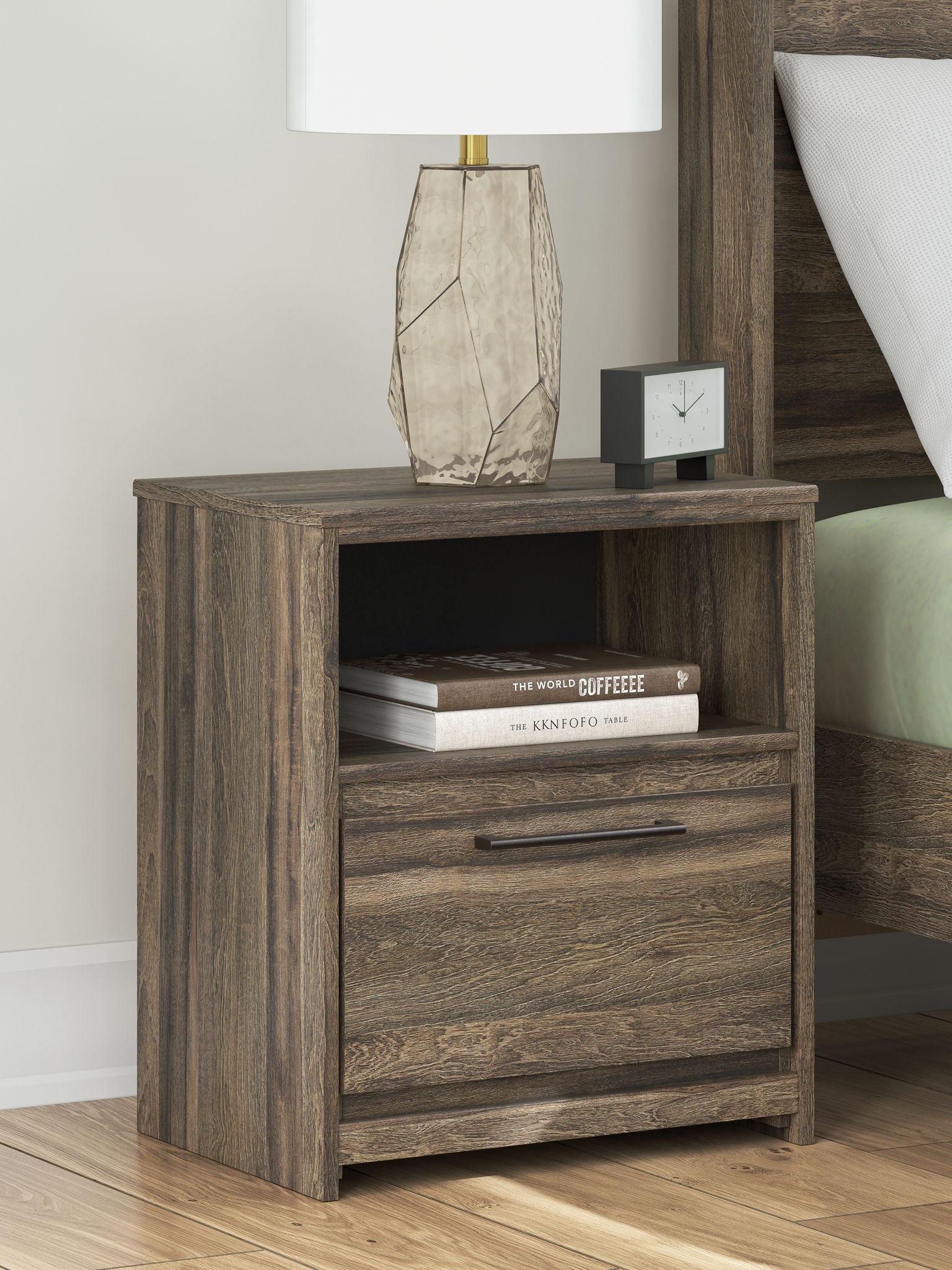 Brown one-drawer night stand with open shelf and drawer; top surface with lamp and books