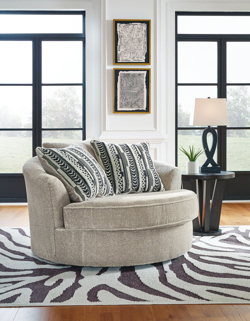 Light beige swivel accent chair with patterned pillows and wide rounded seat