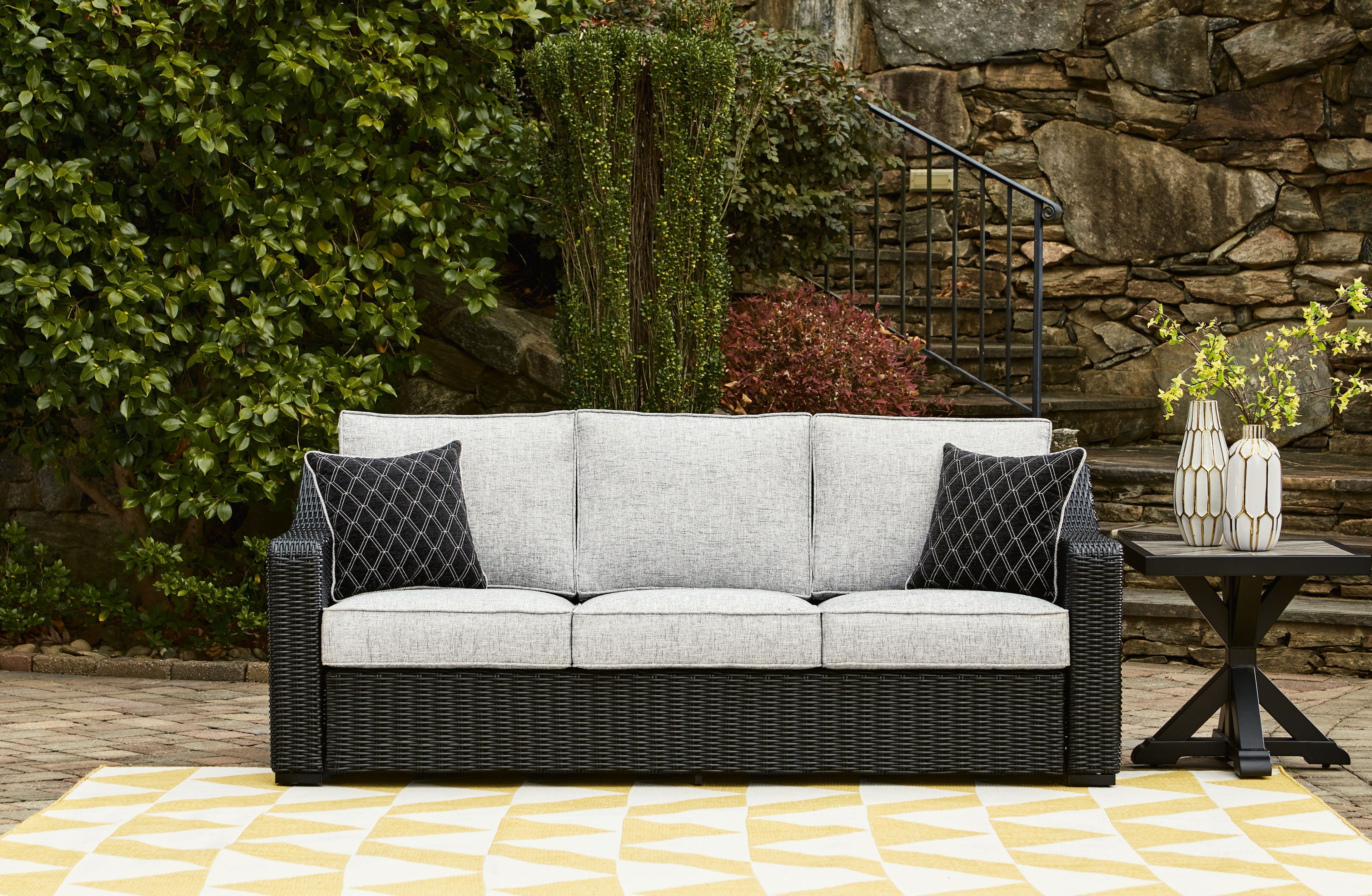 Beachcroft sofa with cushions, dark woven frame, light gray backrests and diamond patterned pillows