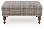 Multi plaid ottoman with smooth upholstered top and dark wooden turned legs