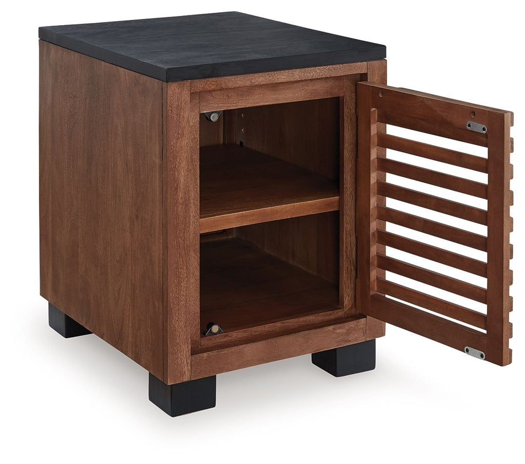 Warm brown end table with black top and open cabinet door with slatted panel