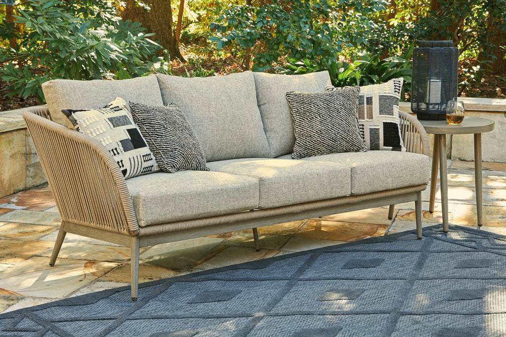 Beige wicker sofa with light gray cushions and patterned throw pillows