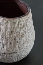 Ceramic vase side view with dark interior opening and striated speckled light gray glaze