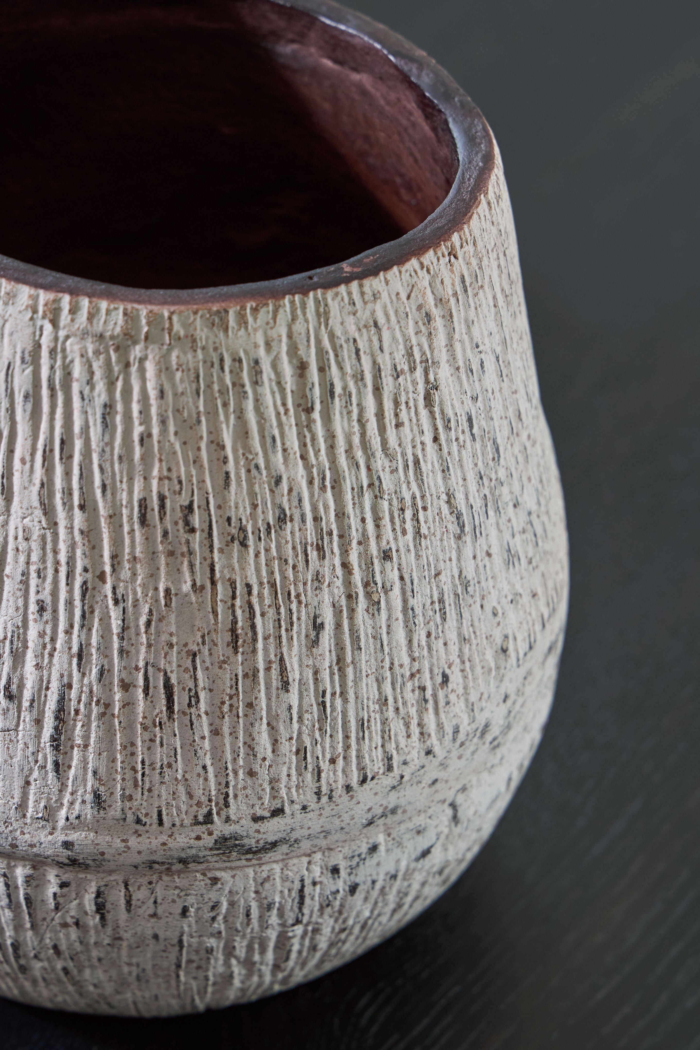 Ceramic vase side view with dark interior opening and striated speckled light gray glaze