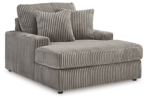 Corduroy chaise lounge chair in dark gray with three cushions and plush seat back.