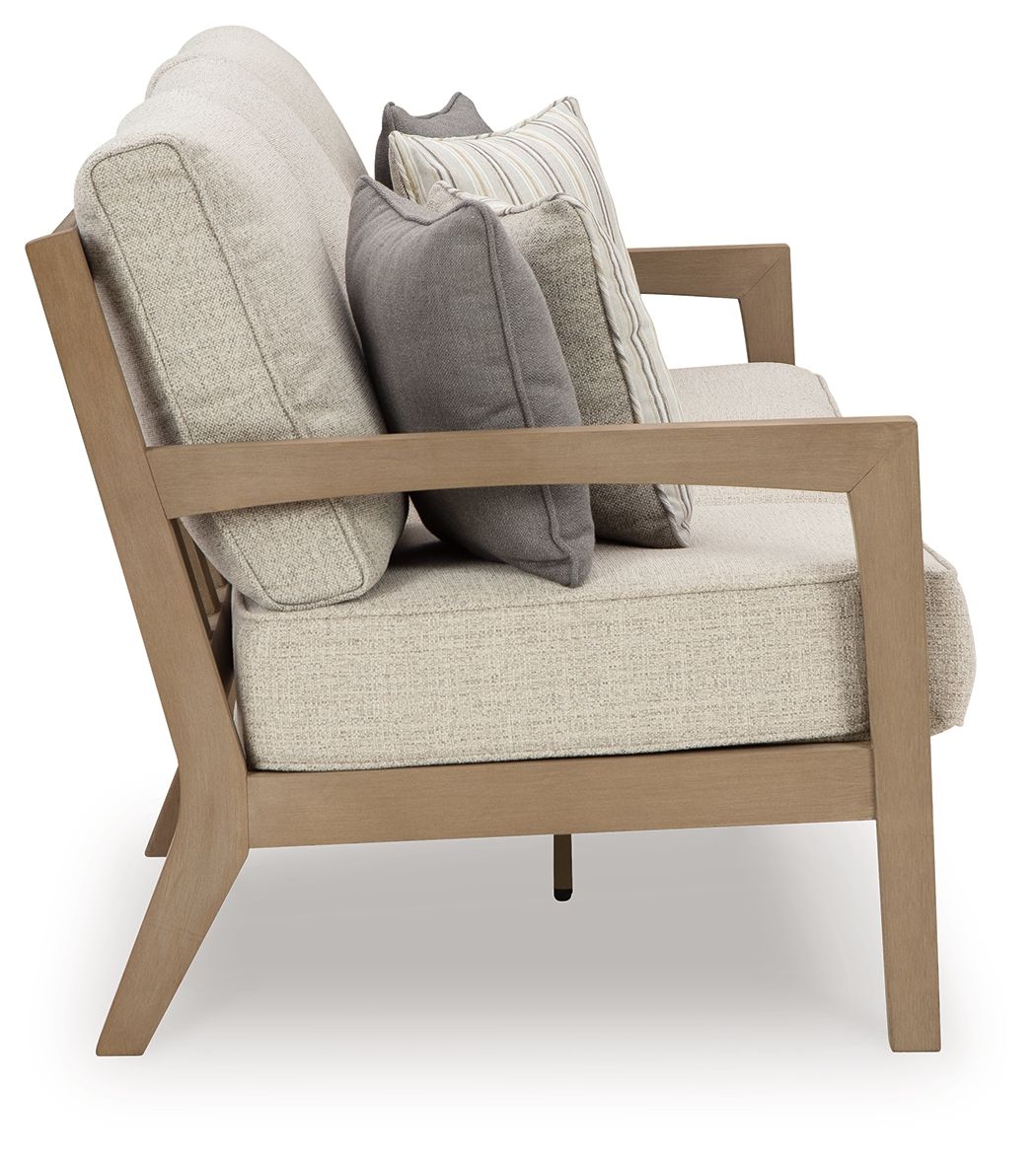 Light beige upholstered loveseat-style sofa with gray and striped throw cushions, wood frame