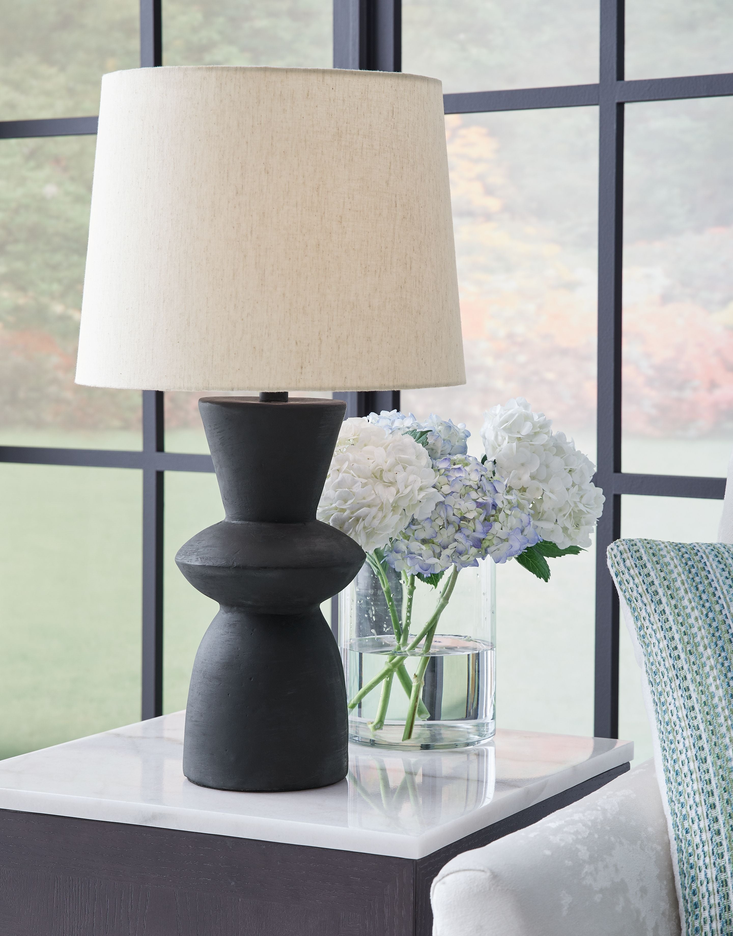 Distressed black paper table lamp with drum shade and sculpted base