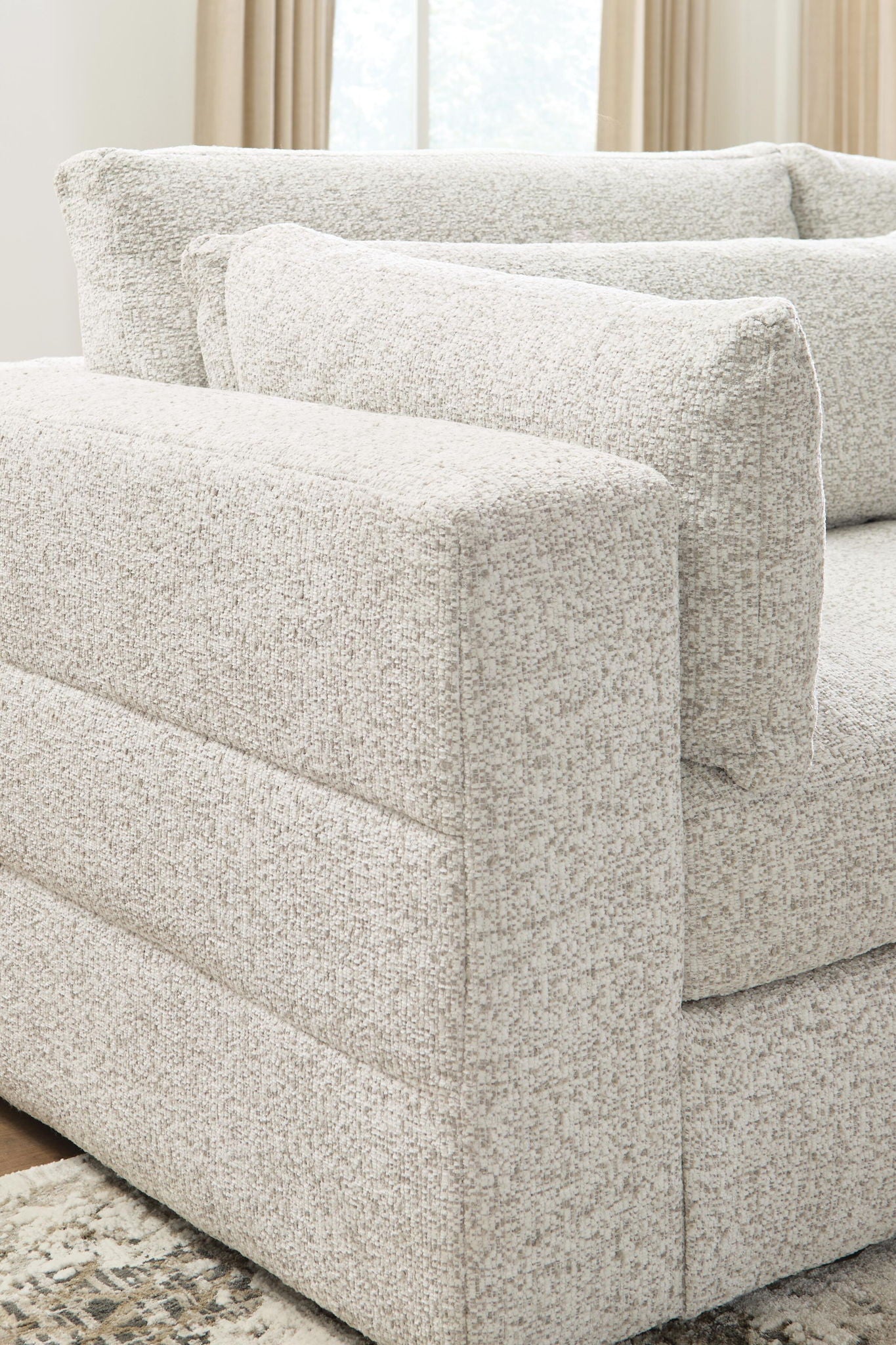 Beige upholstered sectional sofa with squared arm and seat cushion, textured fabric and pillows