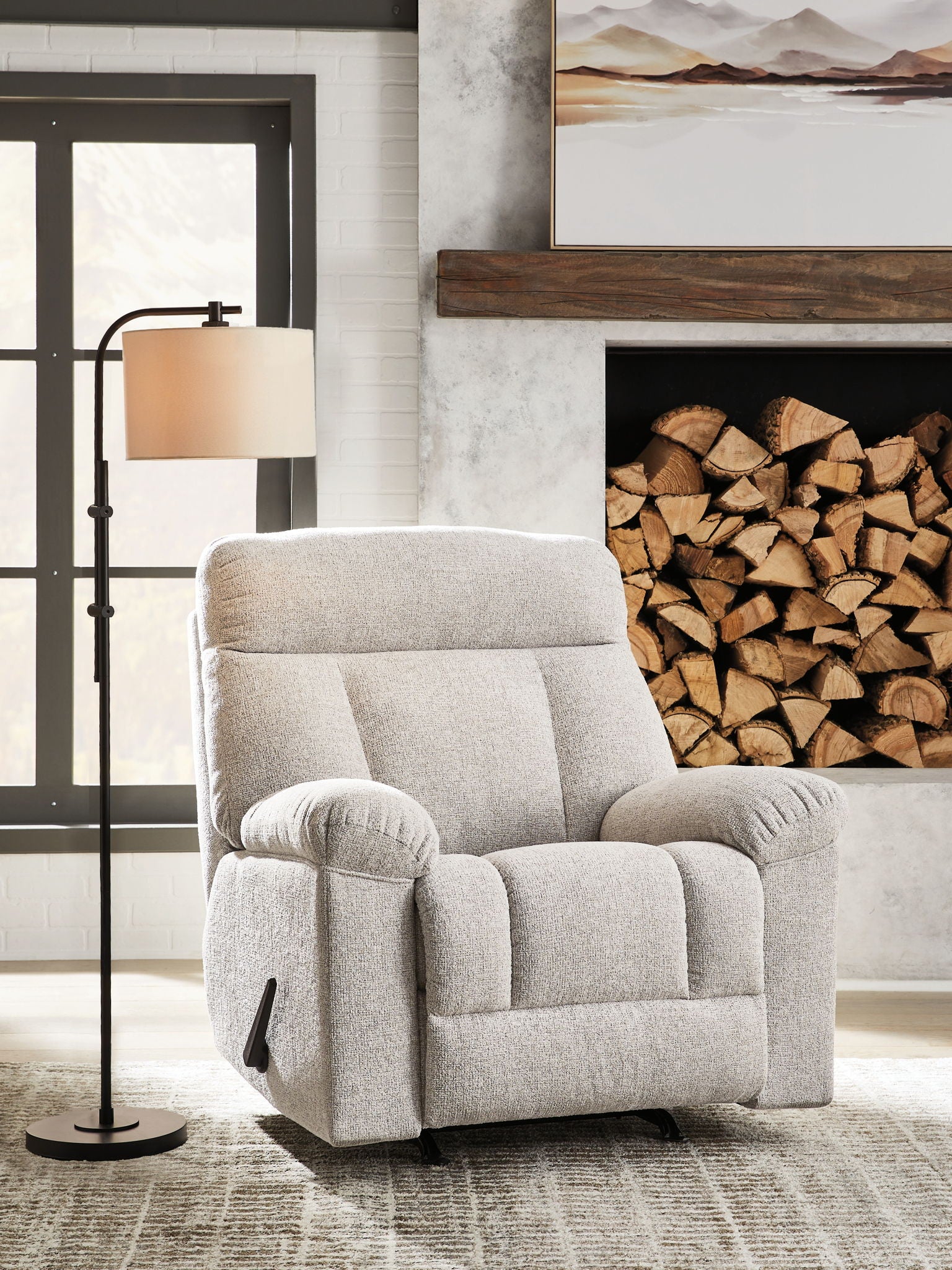 Rocker recliner chair in light gray upholstery with padded track arms and footrest