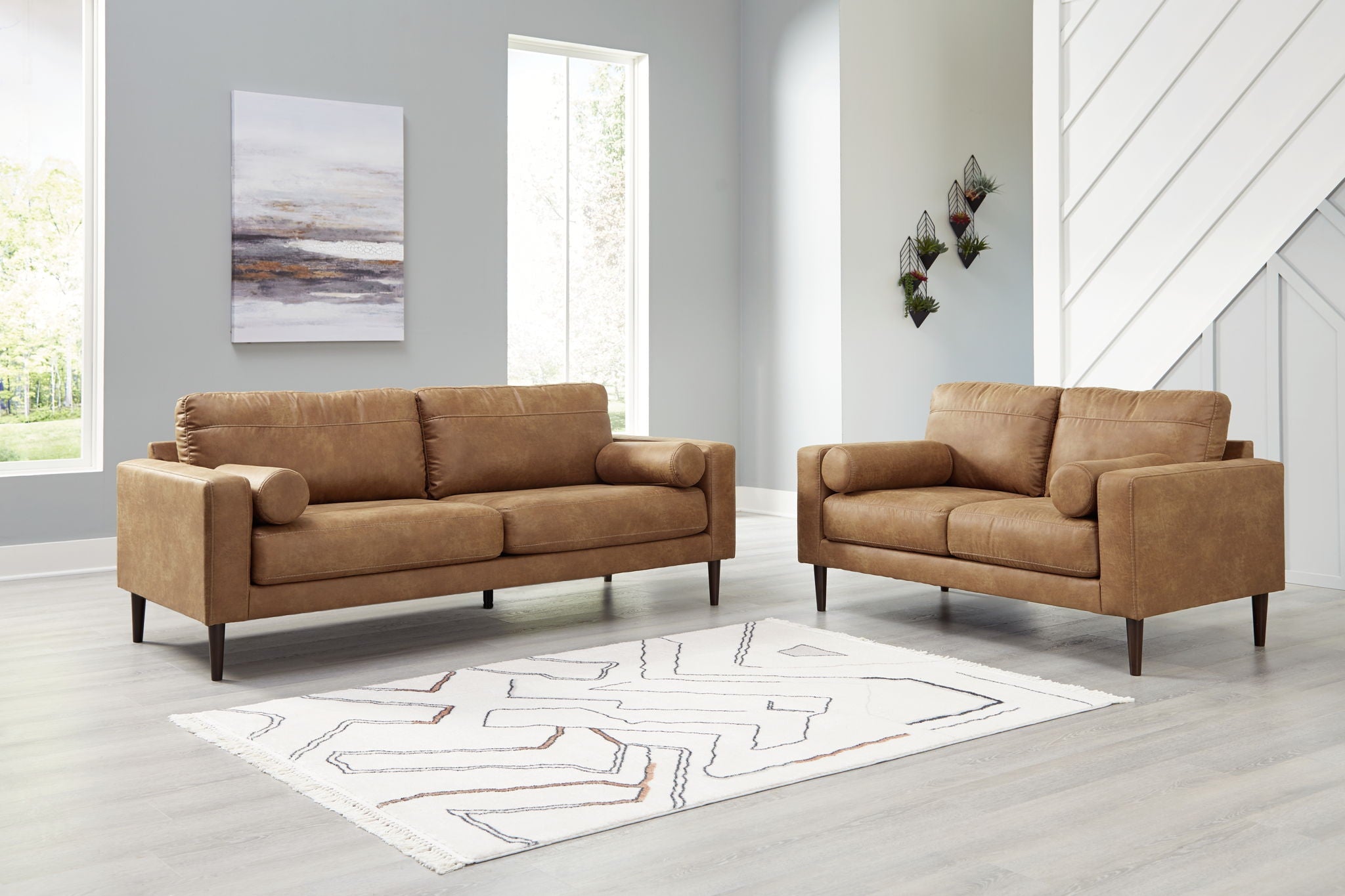 Light brown upholstered sofa and loveseat set with rounded arms and tapered legs