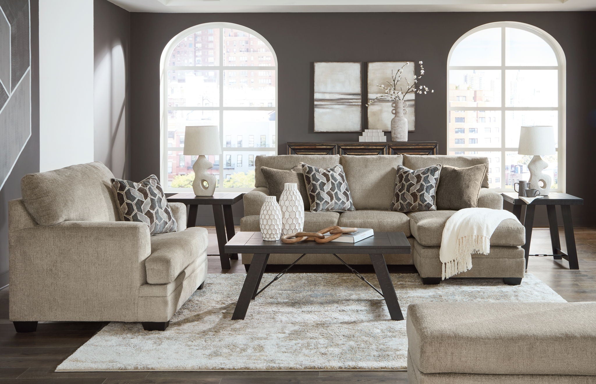 Light brown living room set with sofa, arm chair, and patterned accent pillows