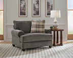 Gray chair-and-a-half with plaid and solid accent pillows and rolled arms