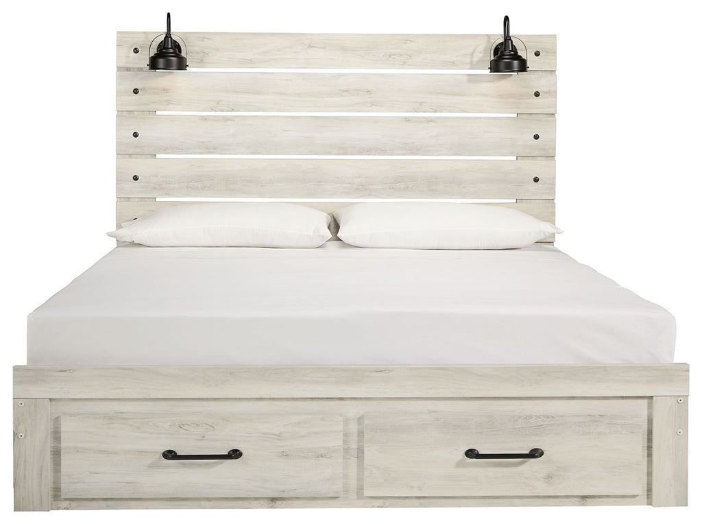 Light wood panel bed with two front drawers; white bedding and two black lamps on headboard