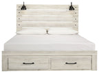 Light wood panel bed with two front drawers; white bedding and two black lamps on headboard