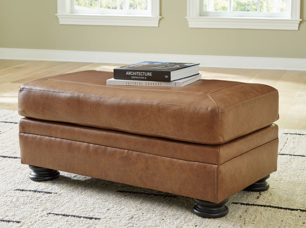 Carianna ottoman with caramel-brown upholstered top and base, dark legs, rounded rectangular form
