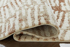 Area rug edge view: cream top with rust pattern and gray backing