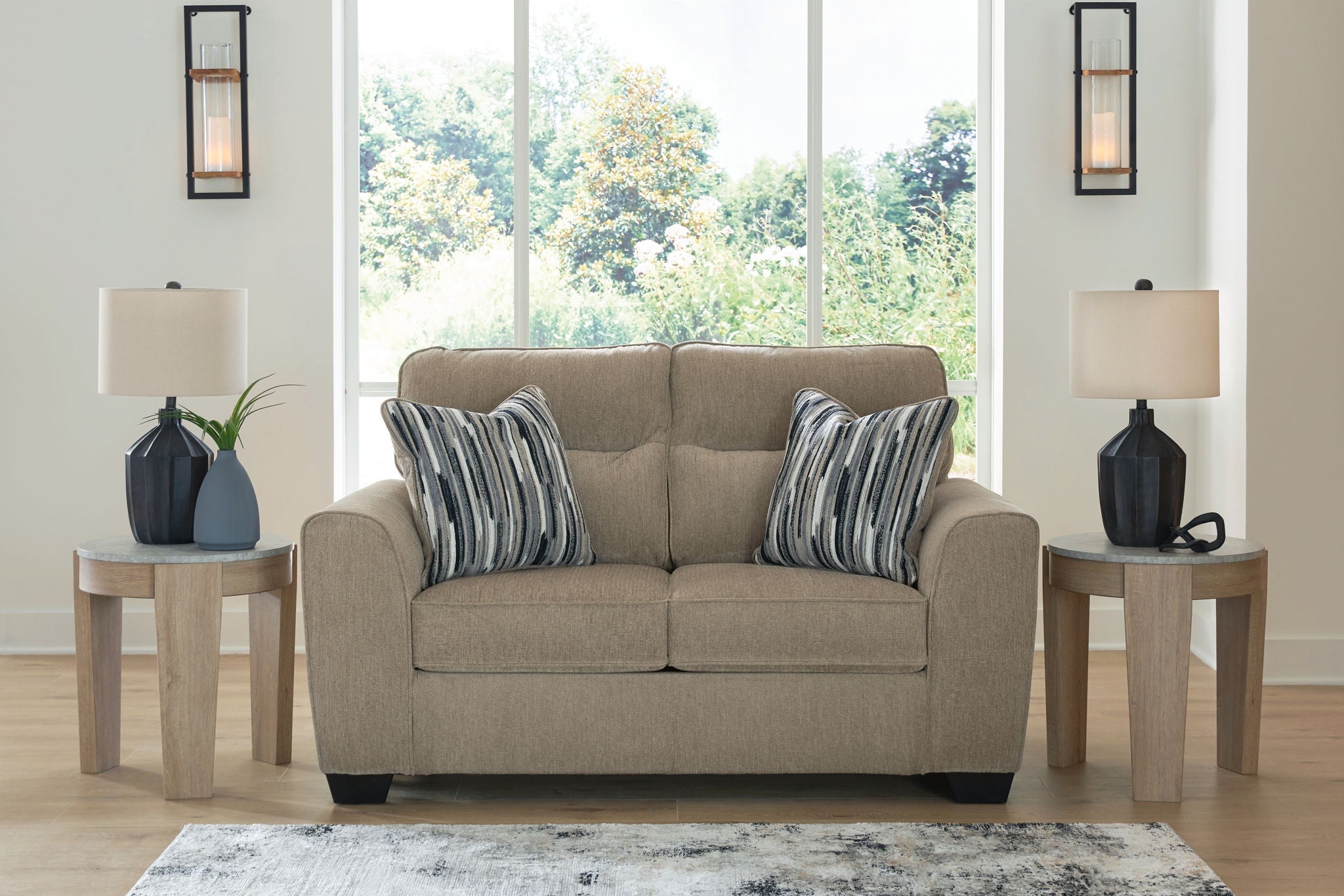 Light brown upholstered loveseat with two seat cushions and striped throw pillows