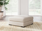 Vanilla upholstered ottoman centered in living room on patterned rug
