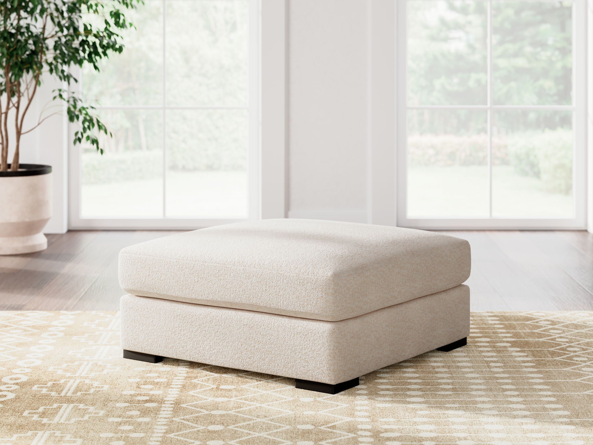 Vanilla upholstered ottoman centered in living room on patterned rug