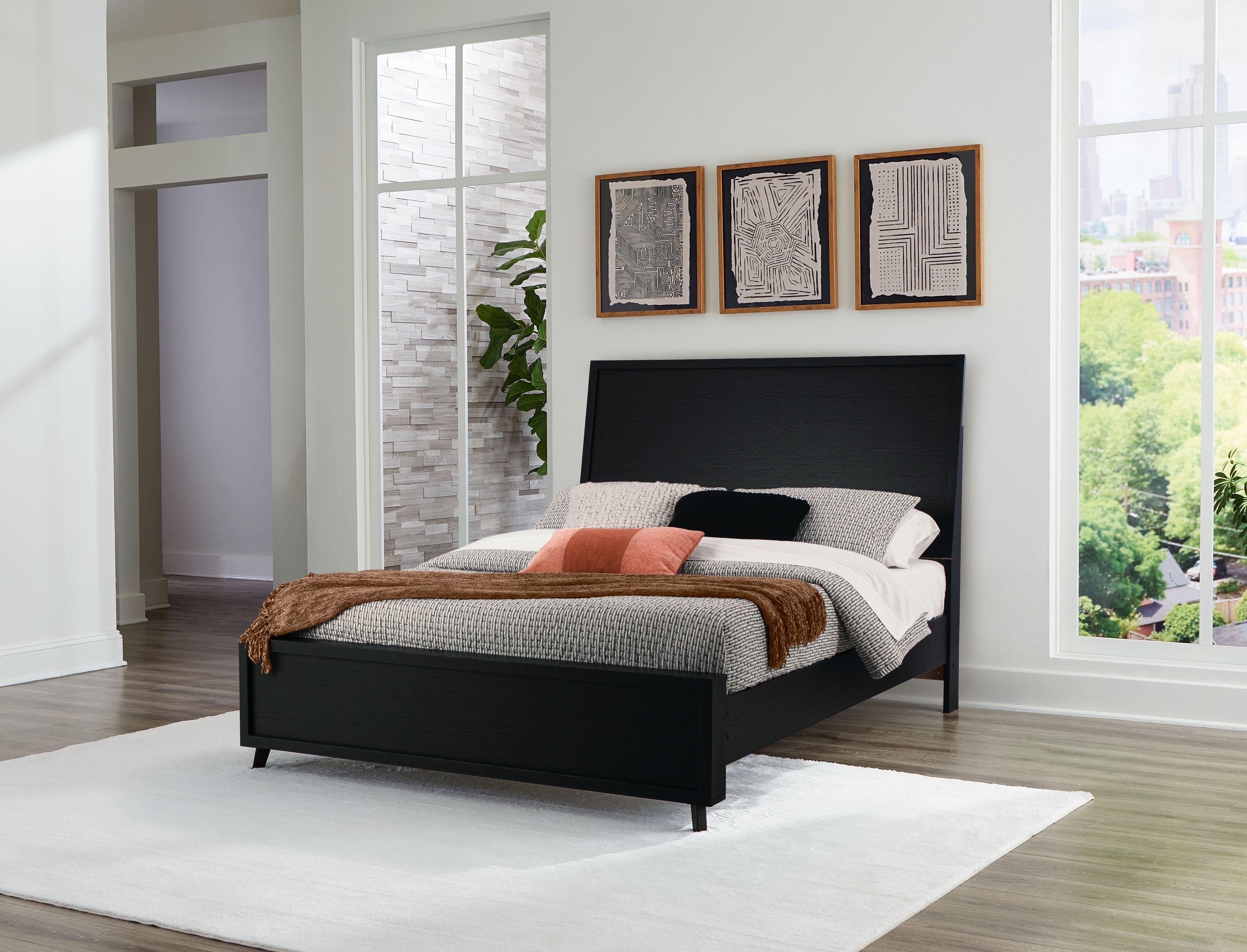 Black panel bed with gray blanket, white sheet, and orange accent pillow