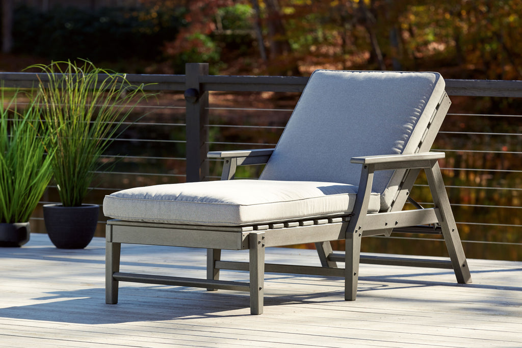 Gray chaise lounge chair with cushion and reclining back, outdoor side view