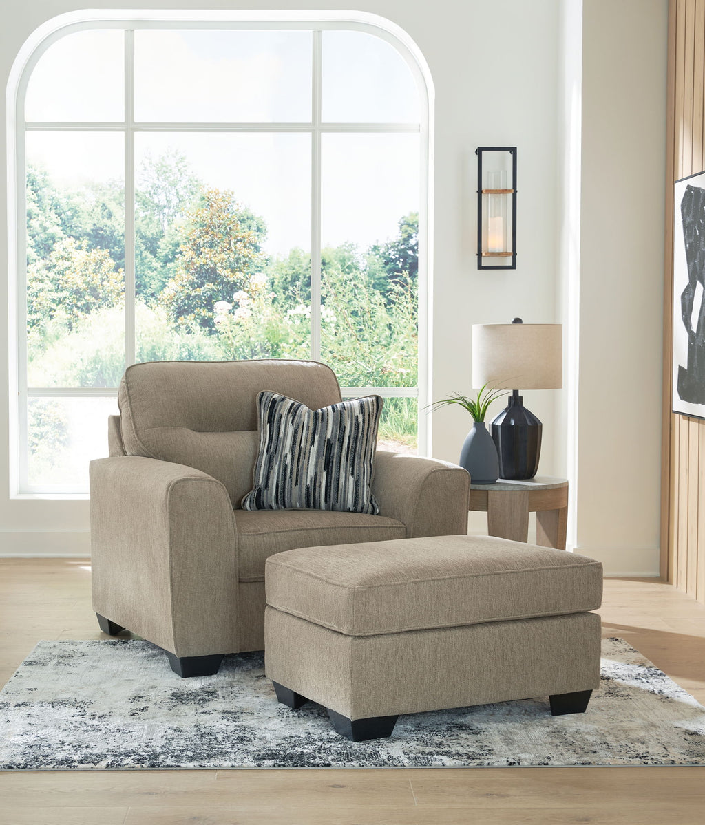 Light brown upholstered armchair with matching ottoman and striped throw pillows