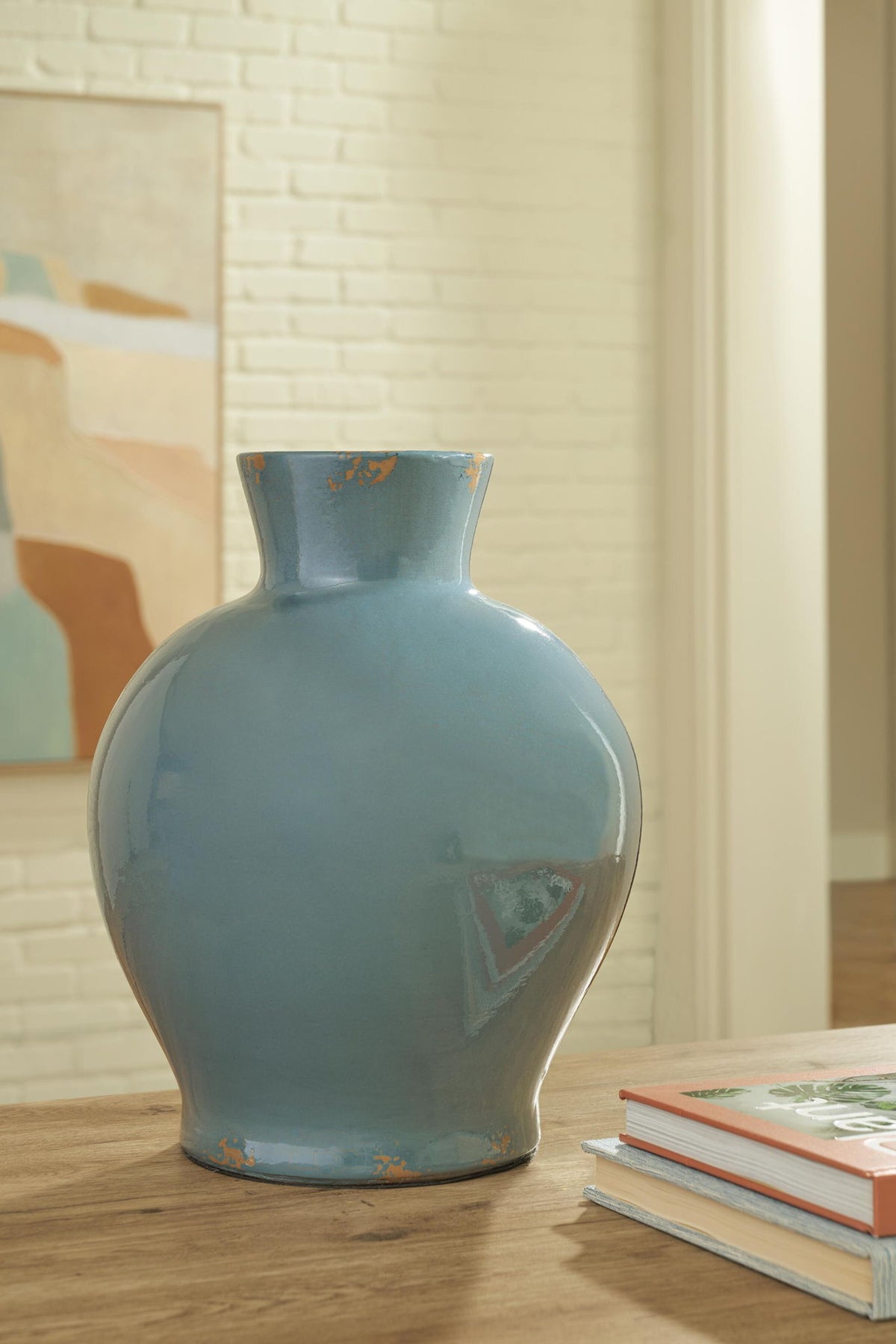 Blue ceramic vase on a table, glossy glaze with distressed orange speckled accents