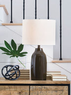 Brown bottle-style table lamp with white drum shade on a wooden console