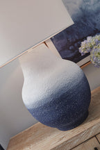Metal table lamp with white drum shade and speckled navy base with textured finish