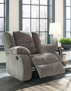 Gray upholstered recliner with padded headrest and footrest, button-tufted back