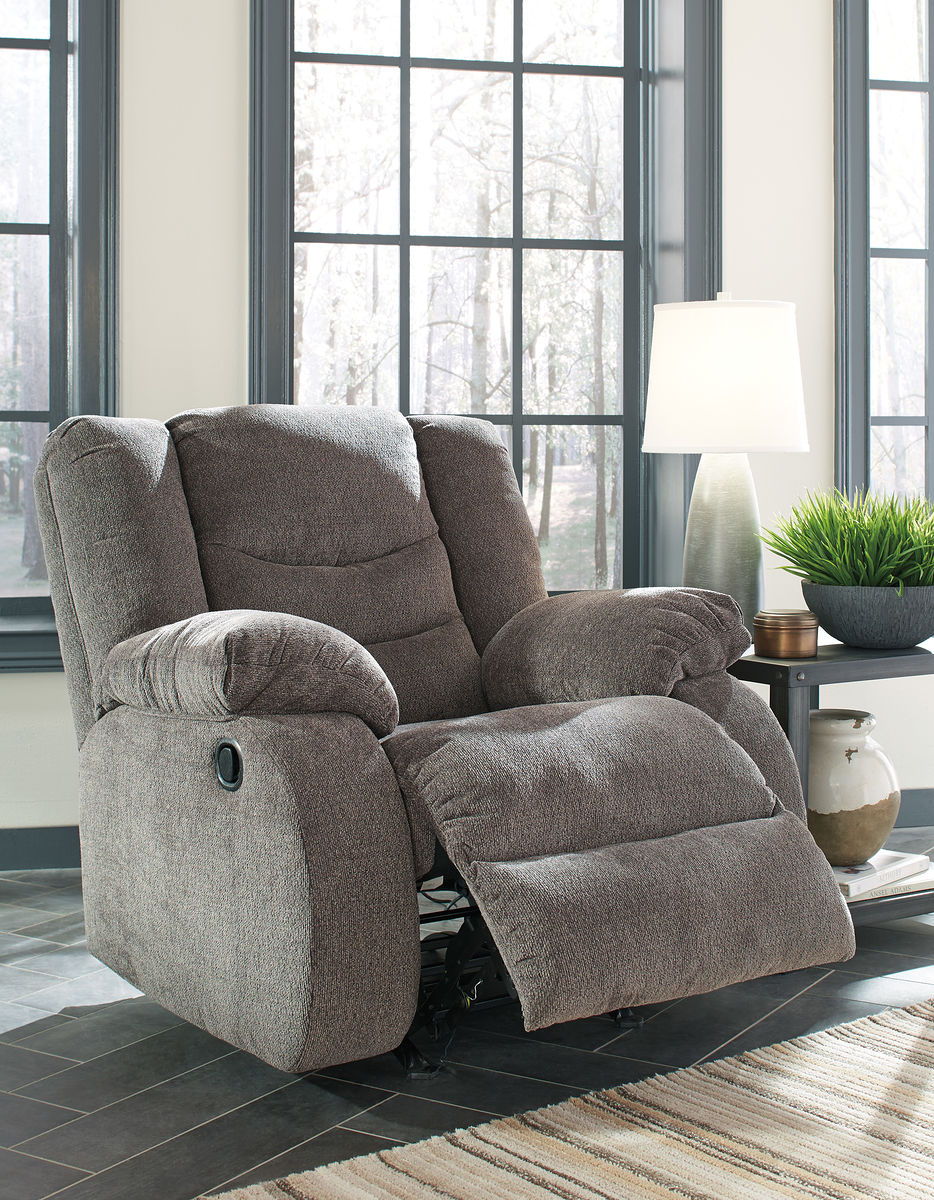 Gray upholstered recliner with padded headrest and footrest, button-tufted back