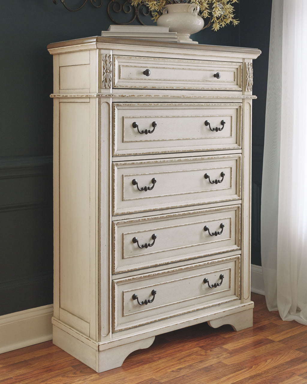 White chest of drawers with decorative trim and black knob hardware