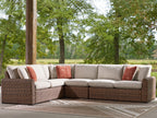 Outdoor sectional sofa with beige upholstery, brown wicker frame, and rust throw pillows