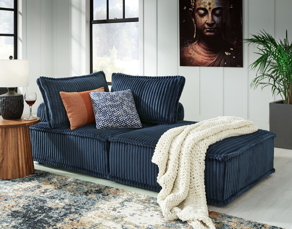 Navy modular sectional sofa with chaise, decorative pillows, and draped throw
