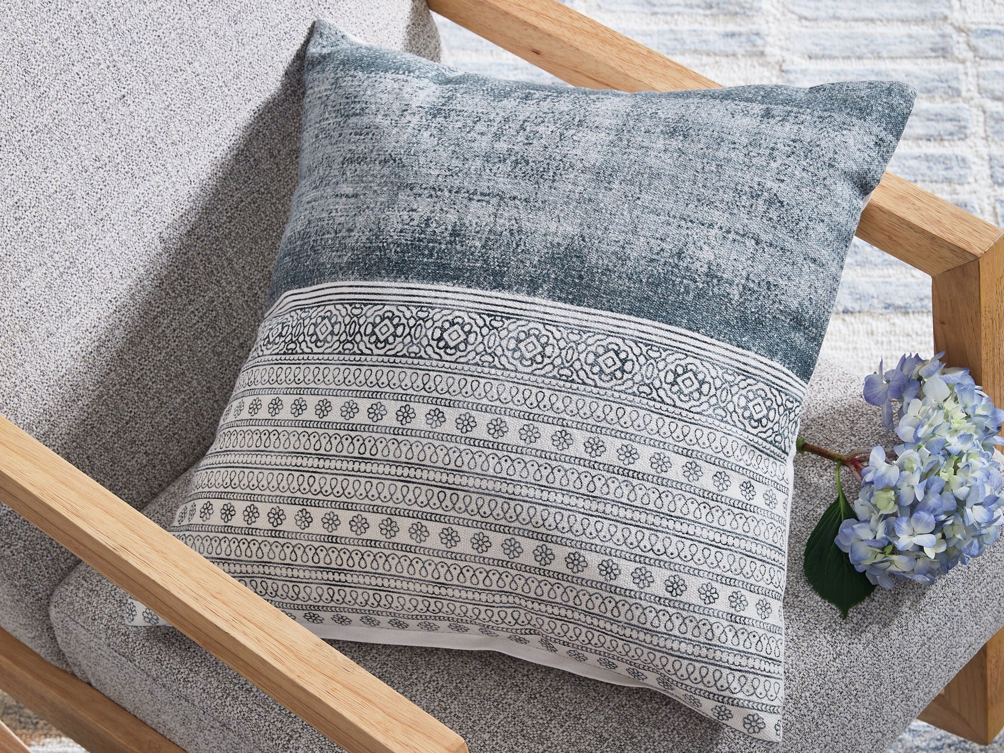 Blue and white patterned throw pillow on chair with horizontal stripe band