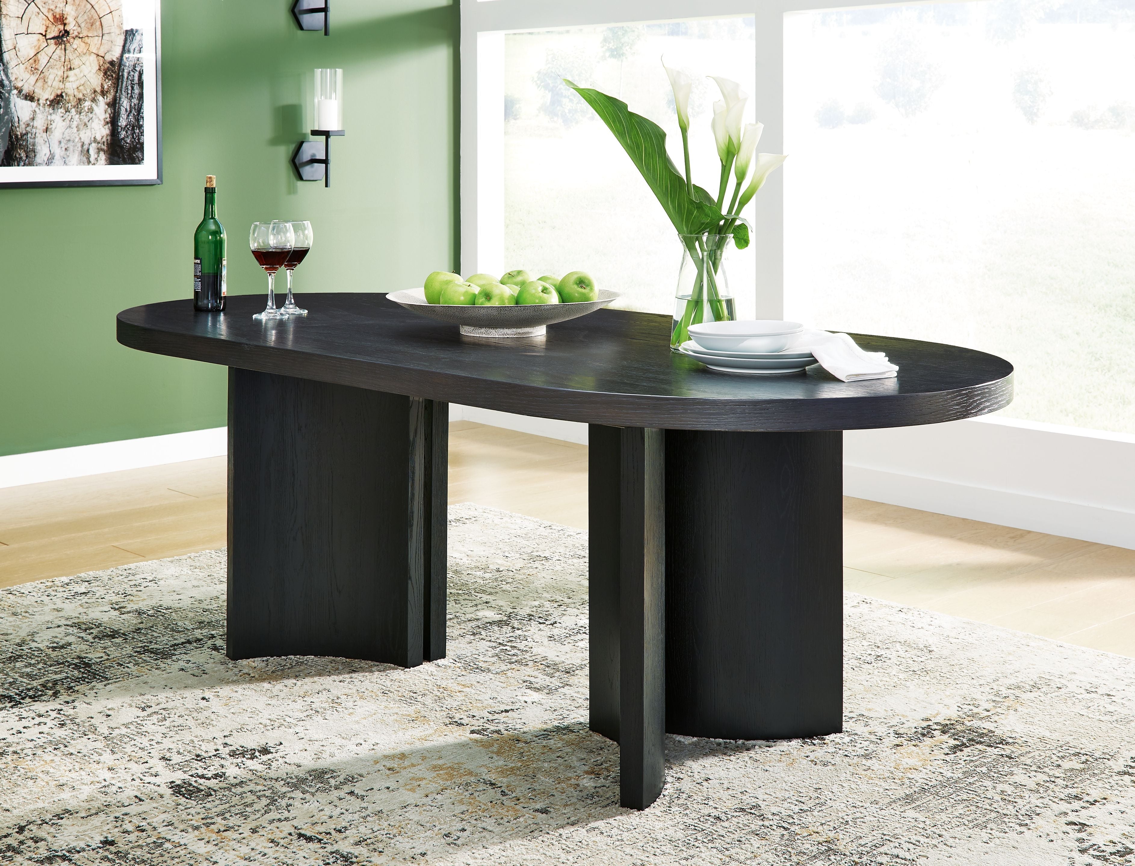 Black oval dining room table with dark wood grain and four pedestal legs