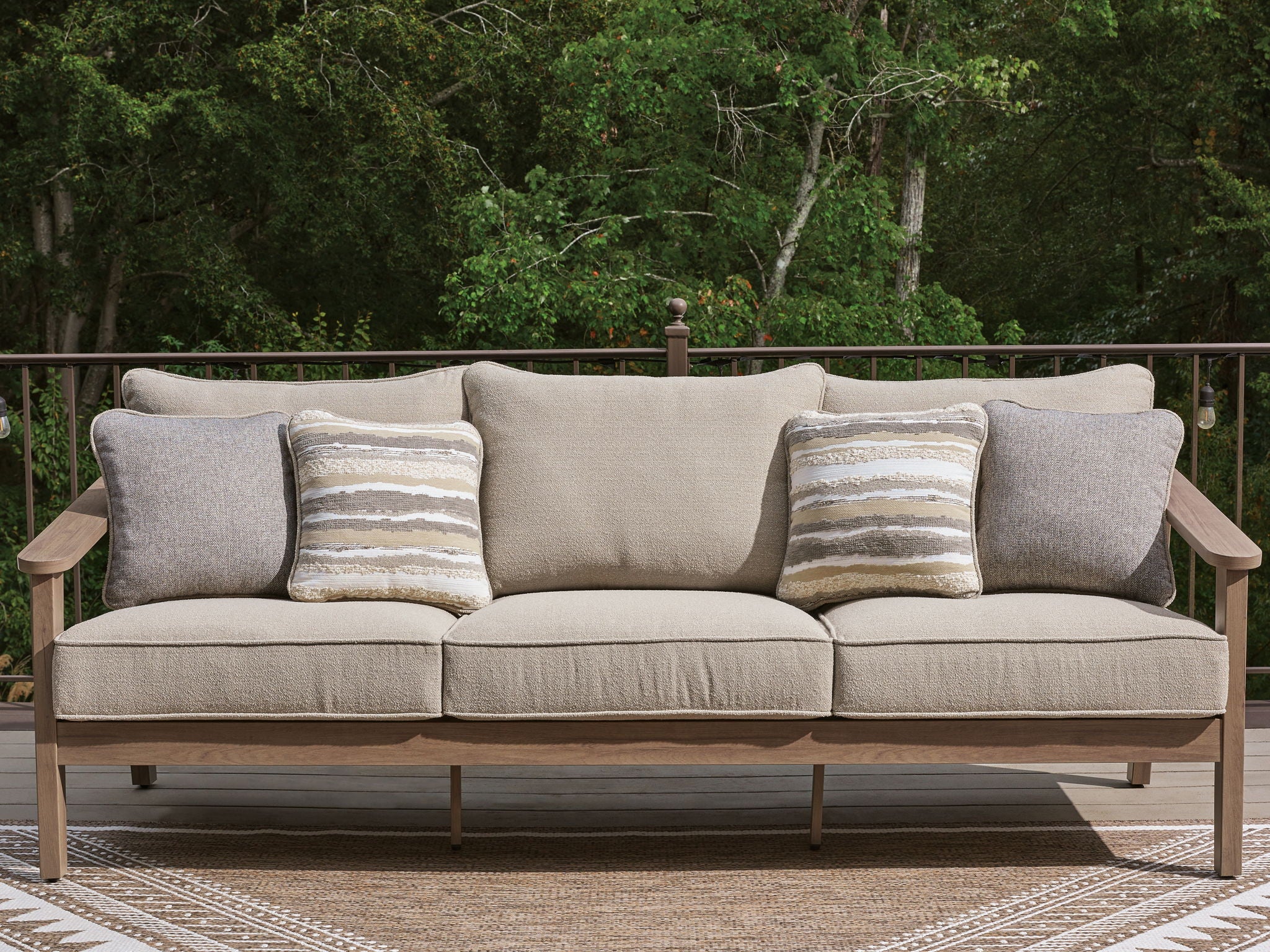 Outdoor sofa with cushions in natural beige, two gray arm cushions, four striped pillows