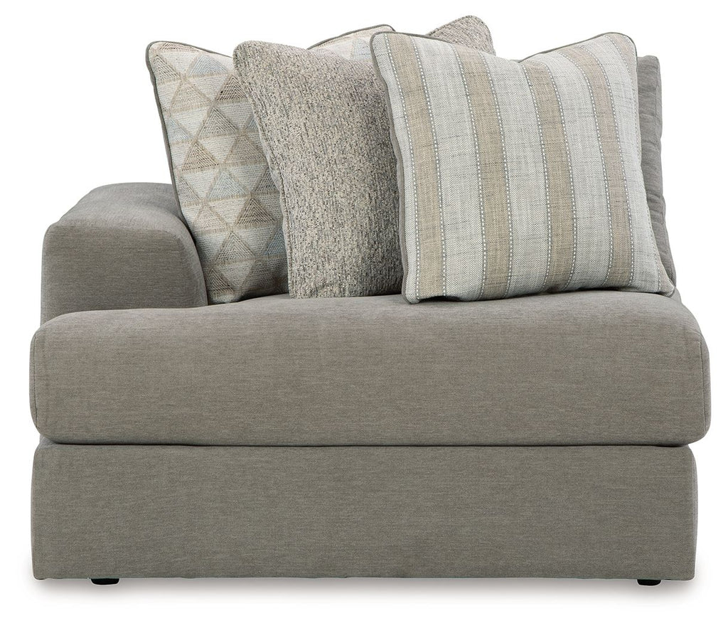 Gray upholstered corner chair with three patterned throw pillows and broad seat cushion