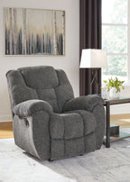 Charcoal fabric rocker recliner with padded arms, headrest, and enclosed footrest