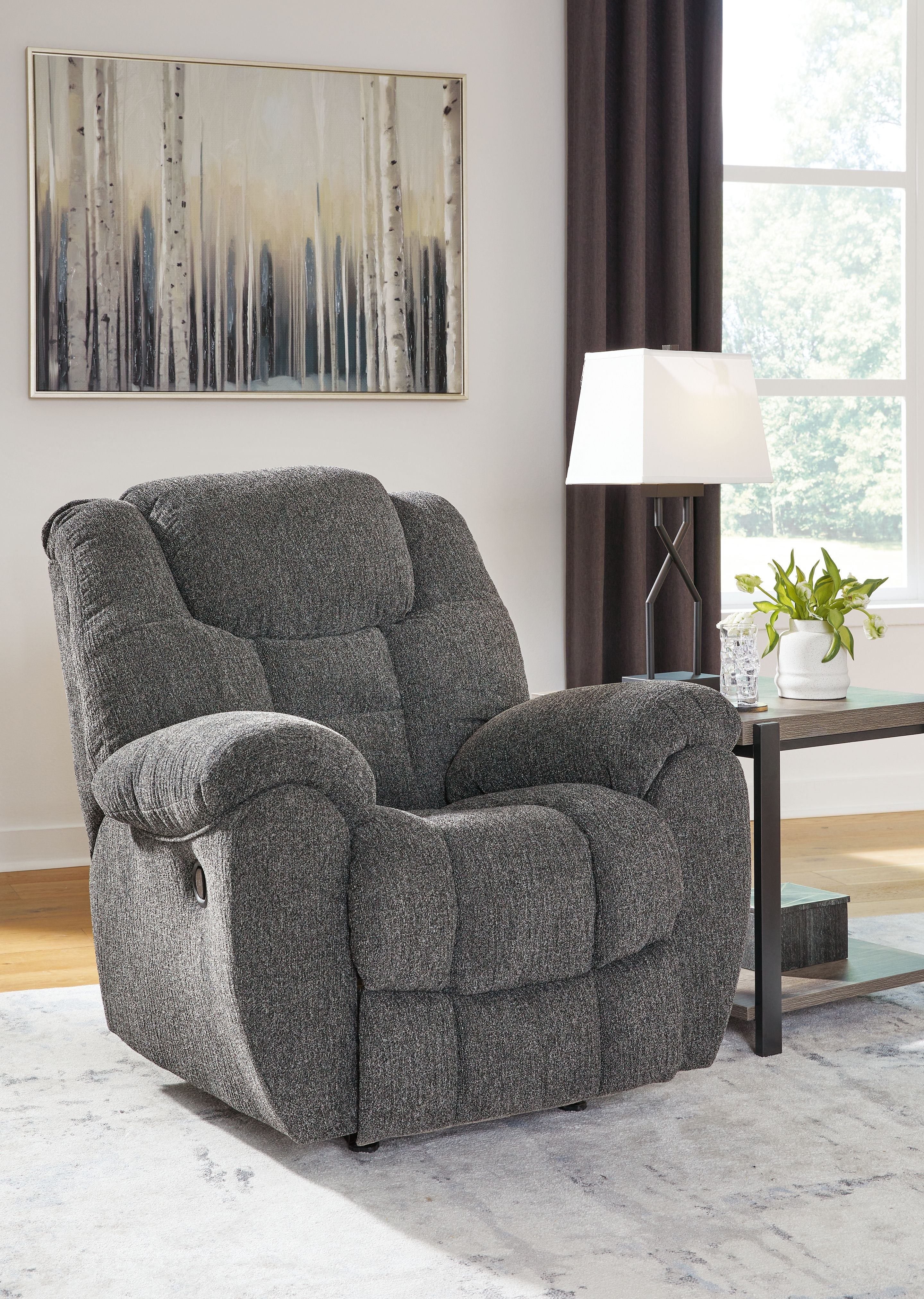 Charcoal fabric rocker recliner with padded arms, headrest, and enclosed footrest
