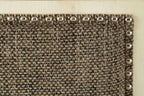 Textured upholstered bench fabric corner with silver nailhead trim along edge