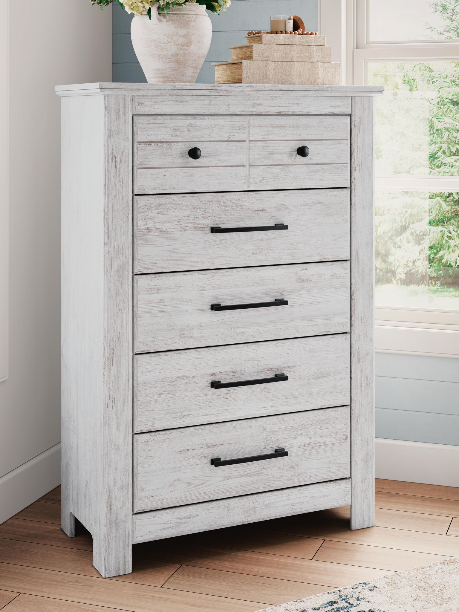 White five-drawer chest with black bar pulls and wide top drawer