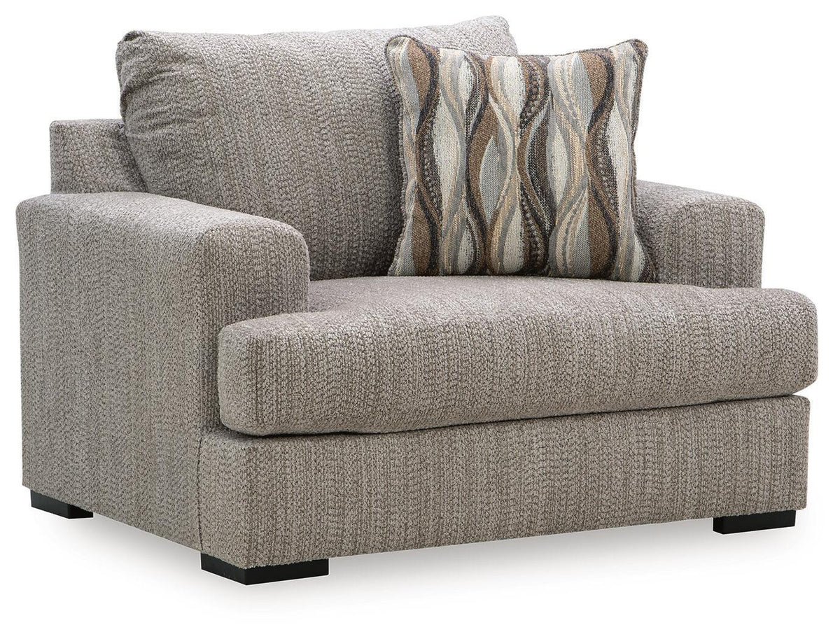 Gray chair and a half with textured upholstery, wide arms, and patterned throw pillow