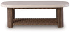 Rectangular cocktail table with light beige round tabletop and woven wicker open shelf