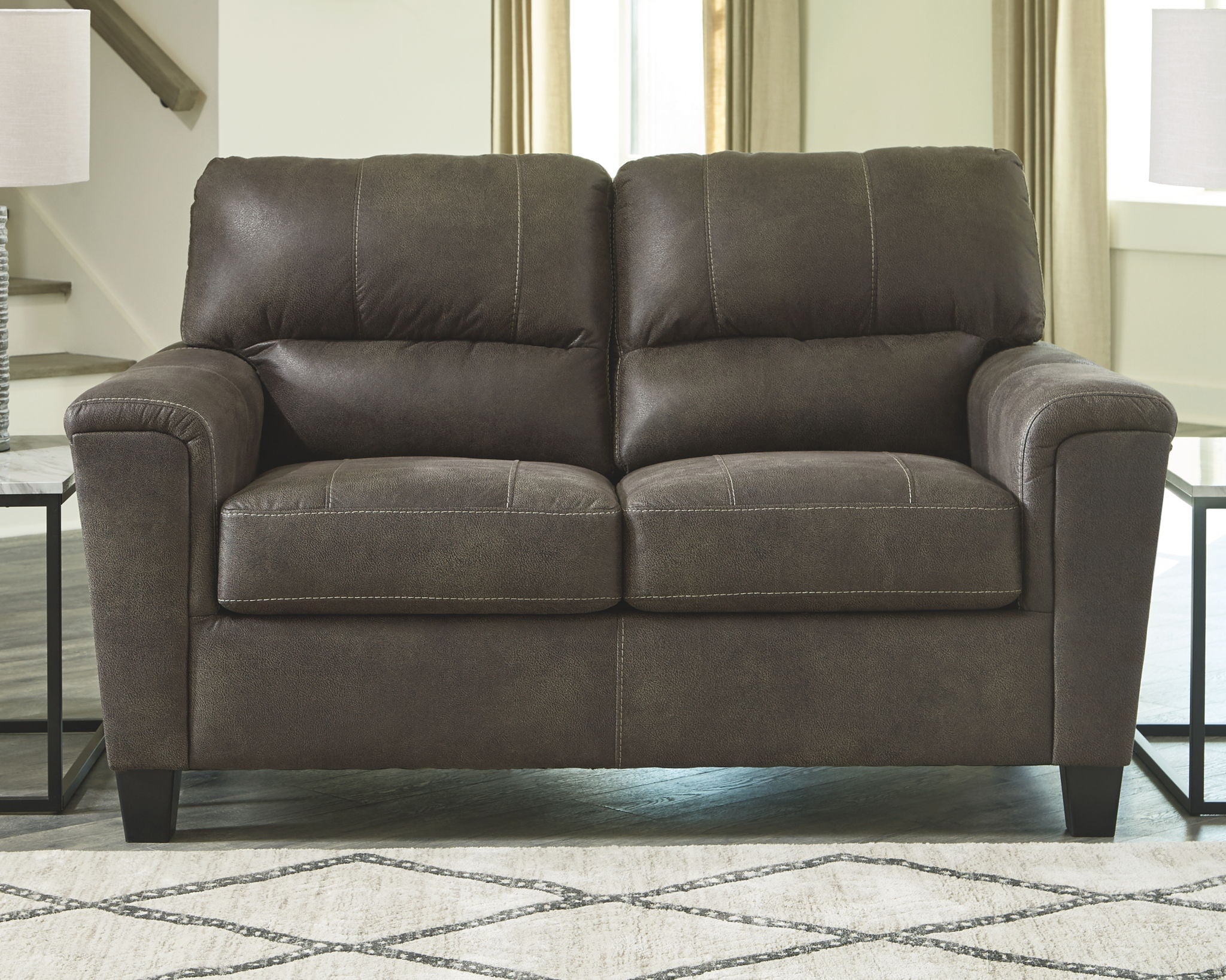 Smoke gray two-seat loveseat with tufted back cushions, padded arms, and dark legs